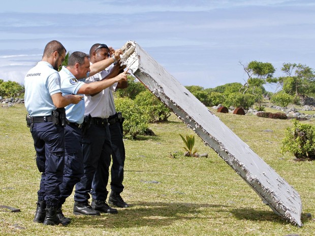 Policiais inspecionam o destroço de aeronave encontrado em Saint-Andre, na ilha de La Reunion, na França. Investigadores identificaram a peça como um 'flaperon', componente da parte traseira da asa, de um Boeing 777, mesmo modelo do voo 370 sumido (Foto: Lucas Marie/AP)