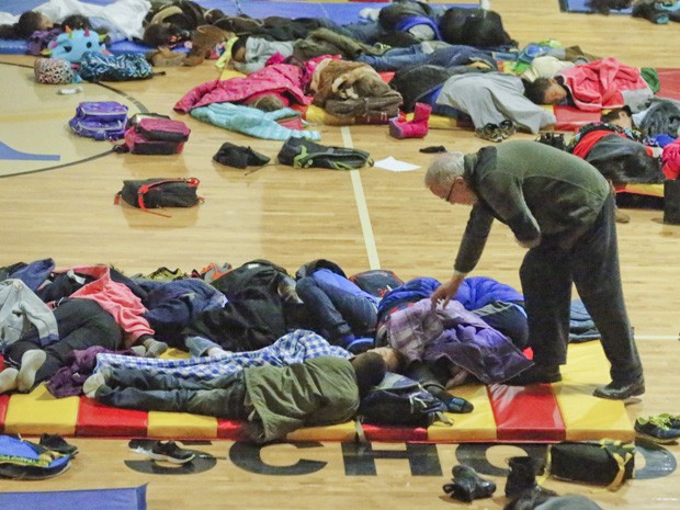 Professor cobre um dos alunos que tiveram que passar a noite acampados na escola após uma tempestade de neve atingr Atlanta. (Foto: John Spink/Atlanta Journal-Constitution/AP)