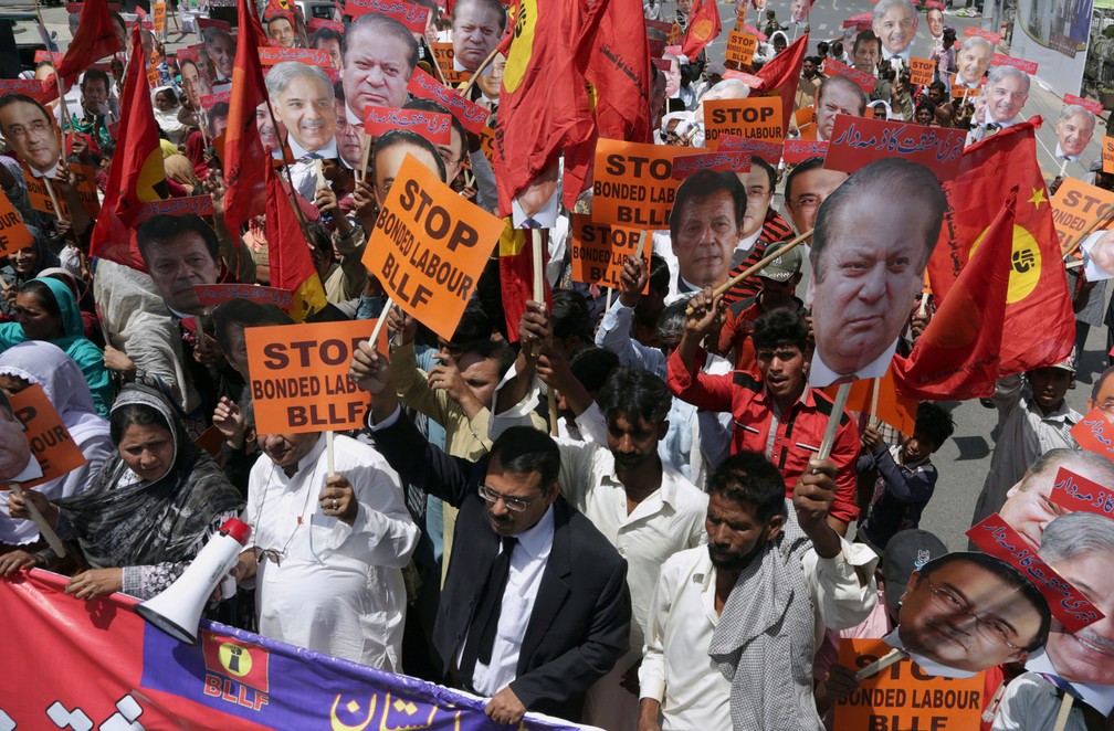 Membros da união trabalhista seguram cartazes com rotos de políticos paquistaneses durante marcha no Dia do Trabalhador em Lahore nesta segunda-feira, dia 1º de maio de 2017 (Foto: K.M. Chaudary/AP)