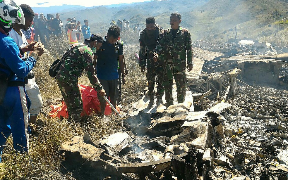 Equipes analisam os destroços do Hercules da Força Aérea da Indonésia que caiu no país neste domingo (18) (Foto: AFP)