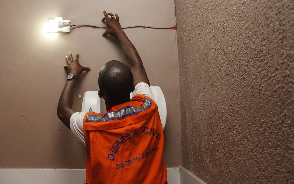 Agente da Defesa Civil verifica estado de fiação elétrica em casa noturna do DF (Foto: Mariana Costa/SSP)