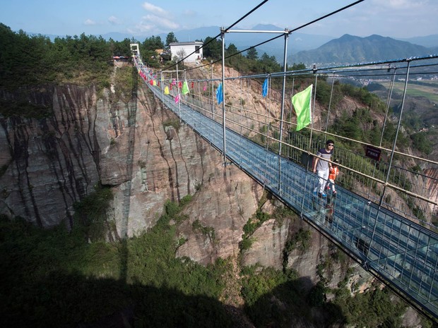 Uma ponte de vidro construída sobre um desfiladeiro a uma altura de 180 metros entre montanhas de Shinuizhai, na China, foi fechada nesta semana após rachaduras aparecerem no local enquanto dezenas de turistas andavam na estrutura recém-reformada (Foto: Johannes Eisele/AFP)