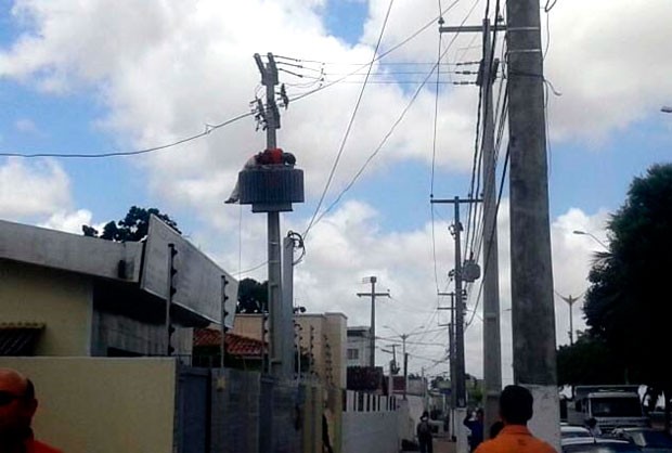 Após levar o choque, homem ficou deitado sobre o transformador preso ao poste (Foto: Vicente Neto)