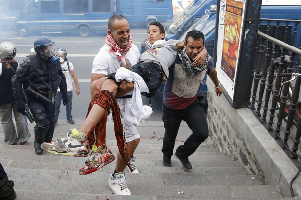 Manifestante é carregado com a perna sangrando na Praça da República, em Paris, durante protesto a favor de Gaza (Foto: François Mori/AP) Manifestante é carregado com a perna sangrando na Praça da República, em Paris, durante protesto a favor de Gaza (Foto: François Mori/AP)