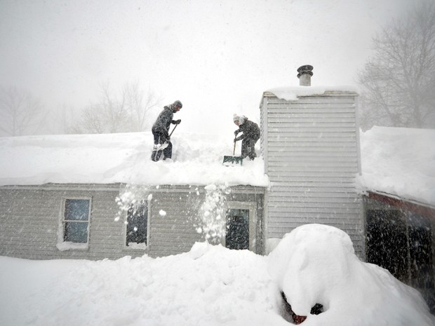  Tami Normile e Richard Brooks tentam tirar o excesso de neve do telhado de sua casa no subúrbio de Lakeview, em Buffalo, NY, na quinta-feira (20) (Foto: John Normile/Getty Images/AFP)