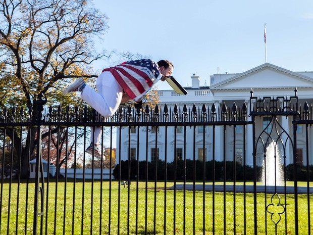 Foto fornecida por Vanessa Pena mostra o momento em que um homem coberto com uma bandeira americana pulou as grades da Casa Branca nesta quinta-feira (26) (Foto: Vanessa Pena via AP)