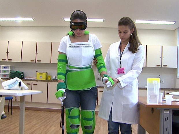 Com simulador de velhice, estudante de enfermagem recebe ajuda de colega para se locomover (Foto: Carlos Trinca /EPTV)