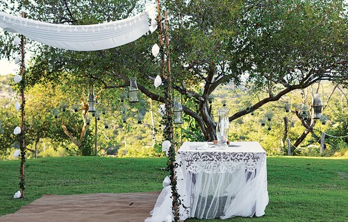 Várias lanternas foram penduradas na árvore sobre a mesa, que recebeu uma toalha branca de renda. Tudo para criar um altar com atmosfera romântica