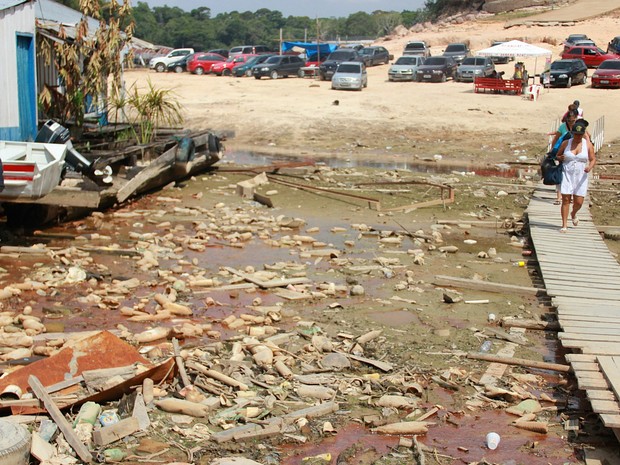 Passageiros de embarcações caminham em passarela improvisada em meio a lixo na Marina do Davi (Foto: Marcos Dantas/G1 AM)