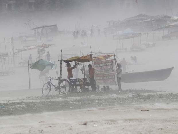 Homem segura lona de sua tenda armada em uma margem do rio Ganges durante tempestade de areia nesta segunda-feira (13) em Allahabad, na Índia (Foto: REUTERS/Jitendra Prakash)