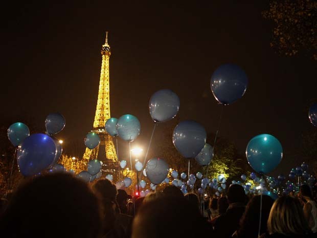 Pessoas seguram balões em frente à Torre Eiffel durante a &#39;Marche des Lumières&#39;, caminhada contra o câncer organizada pelo Instituto Curie, em Paris, na noite de sábado (22) (Foto: Matthieu Alexandre/AFP)