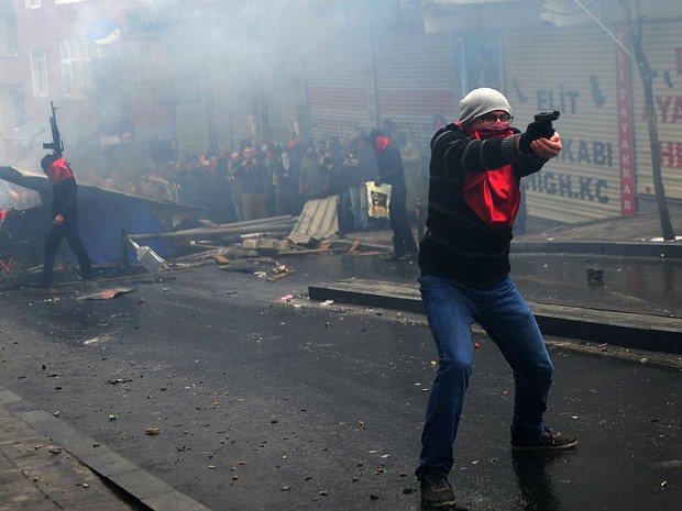 Manifestante a frente de barricada aponta arma em direo  polcia em Istambul, na Turquia. Polcia e ativistas entraram em confronto durante protesto em memria de adolescente morto nas manifestaes de 2013 contra o governo. (Foto: Ozan Kose/AFP)