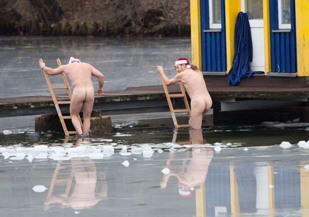 Com gorrinho de Papai Noel, dois alemães nadaram nus na terça-feira (25) nas águas geladas do lago Orankesee em Berlim, na Alemanha. (Foto: Joerg Carstensen/AFP)