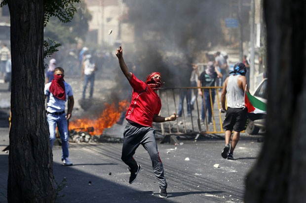 Palestino joga pedras durante confronto com a polícia em Jerusalém nesta sexta-feira (4) (Foto: Baz Ratner/Reuters)