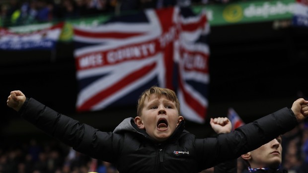 Menino torcedor do Rangers vibra diante da bandeira do Reino Unido