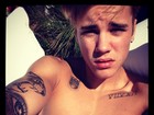 Justin Bieber toma banho de sol sem camisa e exibe tatuagens
