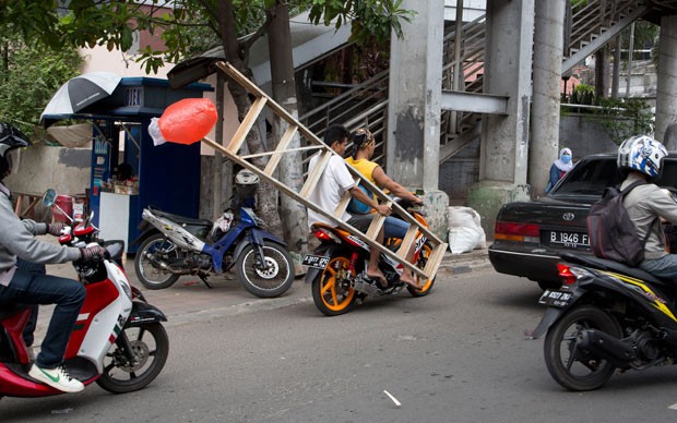 Dupla arrumou jeitinho e carregou escada em moto na Indonésia (Foto: Mark Baker/AP) Dupla arrumou jeitinho e carregou escada em moto na Indonésia (Foto: Mark Baker/AP)