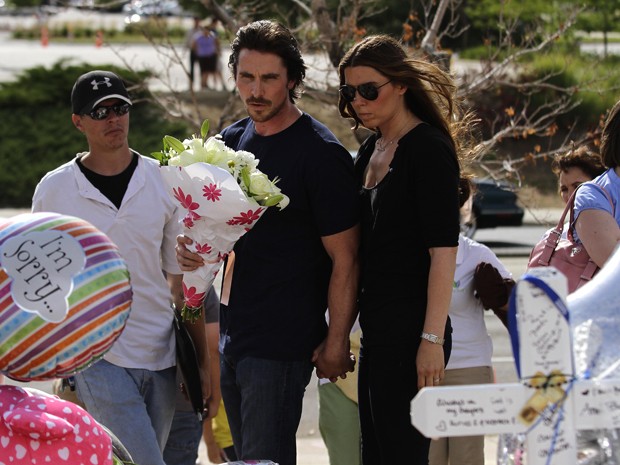 Christian Bale e sua esposa, Sibi Blazic, visitam o memorial na rua do cinema onde houve o massacre