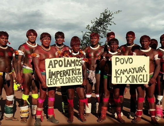 Índios da Terra Indígena do Xingu posam para foto com cartaz em apoio à escola de samba carioca Imperatriz Leopoldinense. Escola desfilará com um enredo sobre defesa da floresta e enfrenta críticas de setores do agronegócio (Foto: Divulgação/Imperatriz Leopoldinense/Facebook)