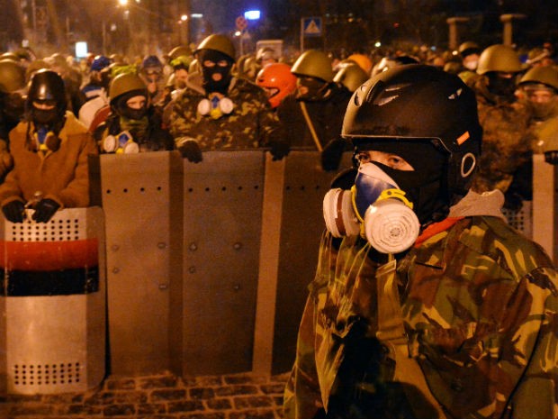Manifestante ficam de guarda e montam barricadas no centro de Kiev na madrugada desta sexta-feira (24). (Foto: Serguei Supinsky/AP)