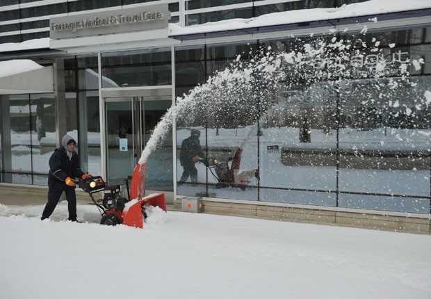 Homem usa equipamento para remover neve e abrir caminho em calçada de Washington DC (Foto: Mandel Ngan/AFP)