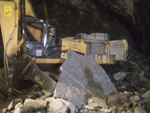 Pedra que matou Alerxsandro teria aproximadamente a metade do tamanho desta em frente à escavadeira (Foto: Arquivo Pessoal)