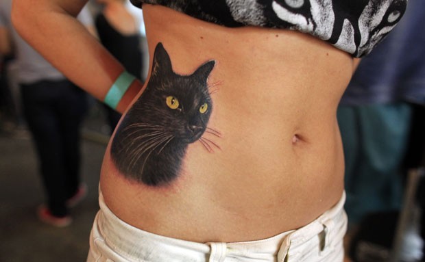 Uma participante exibiu uma tatuagem de um gato na parte lateral do abdômen durante uma feira de tatuagens, no sábado (12), na cidade de Bucareste, na Romênia (Foto: Radu Sigheti/Reuters)