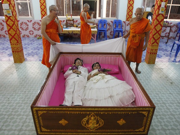 Tanapatpurin Samangnitit e Sunantaluk Kongkoon deitam em caixão durante cerimônia de casamento em Bangcoc, na Tailândia (Foto: Chaiwat Subprasom/Reuters)