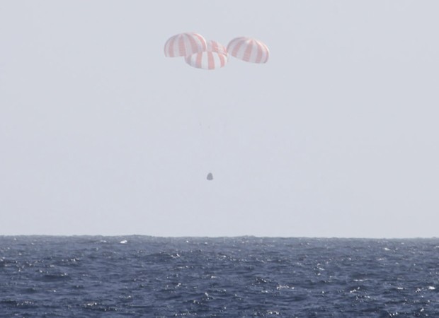 Cápsula Dragon aterissando no oceano com a ajuda de para-quedas (Foto: SpaceX/Reuters)