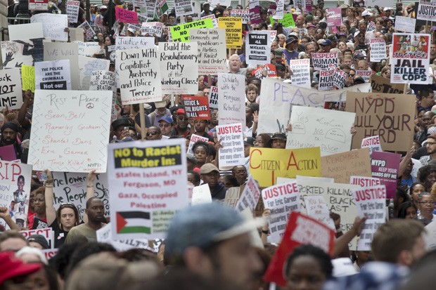 Multidão caminha com cartazes em protesto em Staten Island, nos EUA (Foto: John Minchillo/AP)