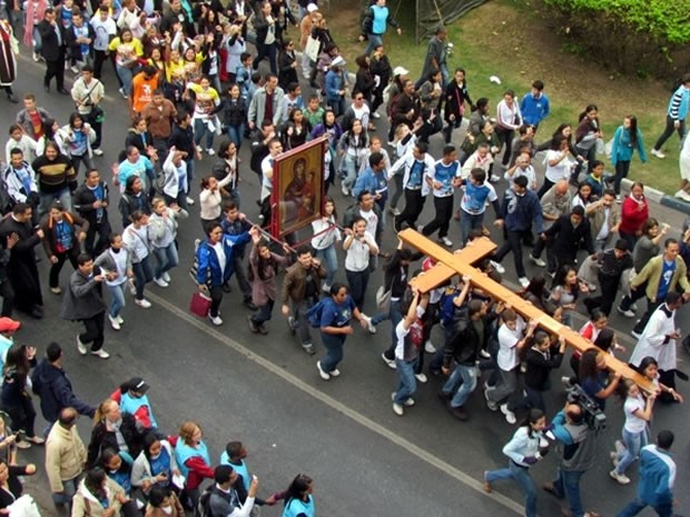 Jovens se revezavam para carregar a cruz de madeira e quadro de Nossa Senhora (Foto: Denise Soares / G1)