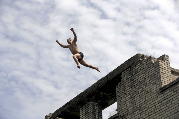 Homem salta para nadar nas ruínas da prisão de Murru, na Estônia (Foto: Ints Kalnins/Reuters)