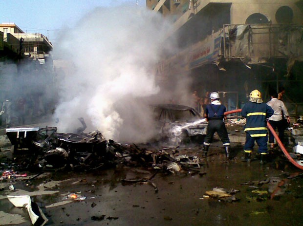 Bombeiros apagam fogo após explosão de carro-bomba nesta segunda-feira (27) em Bagdá, capital do Iraque (Foto: AP)