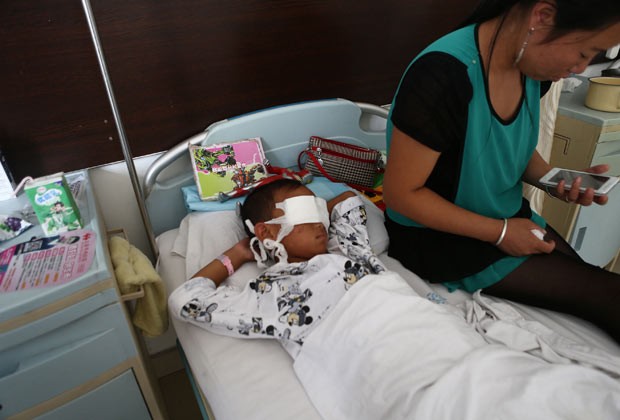 O garoto ao lado da mãe nesta terça-feira (27) em hospital da cidade chinesa de Taiyuan (Foto: AFP)