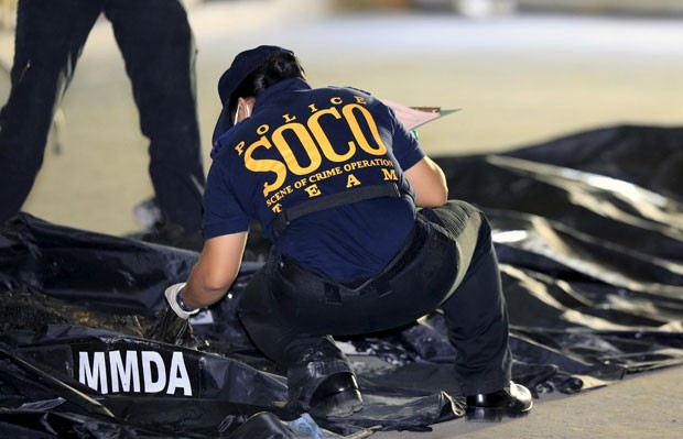 Integrante da equipe de Operações em Cena de Crime (cuja sigla, em inglês, é Soco) examina cadáveres queimados após o incêndio em uma fábrica de Manila (Foto: Romeo Ranoco/Reuters)