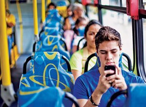 Jovem usa celular durante trajeto de ônibus: 250,8 milhões de linhas ativas (Foto: Reprodução Internet)
