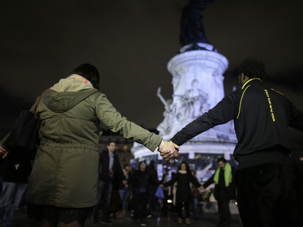 Pessoas dão as mãos durante homenagem aos mortos em atentados de Paris na Place de la Republique, na sexta (20) (Foto: AFP Photo/Kenzo Tribouillard)
