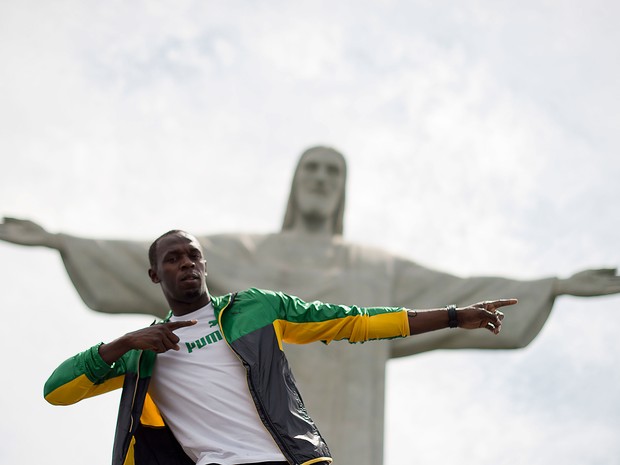 Bolt faz o gesto que é sua 'marca característica' em visita ao Cristo Redentor (Foto: Christophe Simon/AFP)