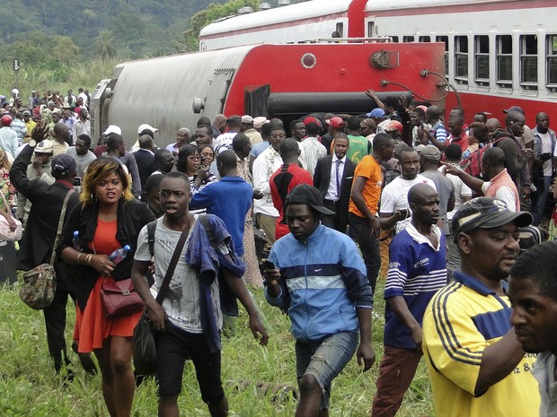 Passageiros de reúnem ao lado de trem que descarrilou nesta sexta-feira (21) nos Camarões (Foto: STRINGER / AFP)