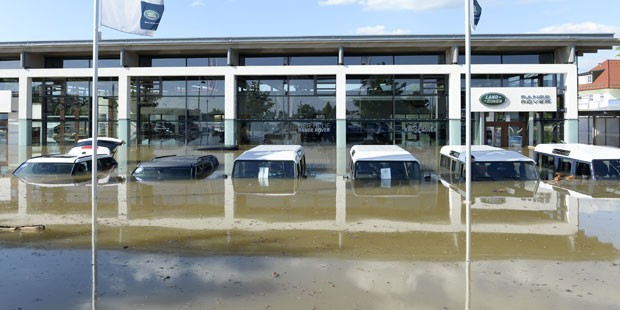 Carros são vistos parcialmente submersos em frente à concessionária da Land Rover na vila alemã de Fischerdorf (Foto: Christof Stache/AFP)