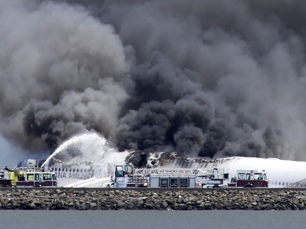 Bombeiros apagam o incêndio iniciado com a queda do Boeing 777, da companhia aérea Asiana Airlines, que ocorreu quando a aeronave aterrisava no aeroporto internacional de San Francisco, EUA, neste sábado (6). (Foto: Bay Area News Group, John Green/Associated Press)