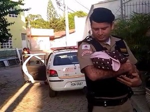 Policial segura criança que foi abandonada em Governador Valadares (MG). (Foto: Inter TV dos Vales/Reprodução)