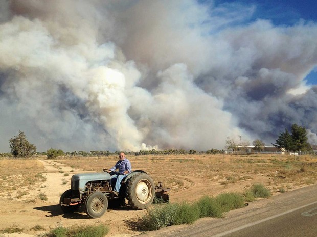 Fazendeiro e o incêndio ao fundo (Foto: Gene Blevins / Reuters)