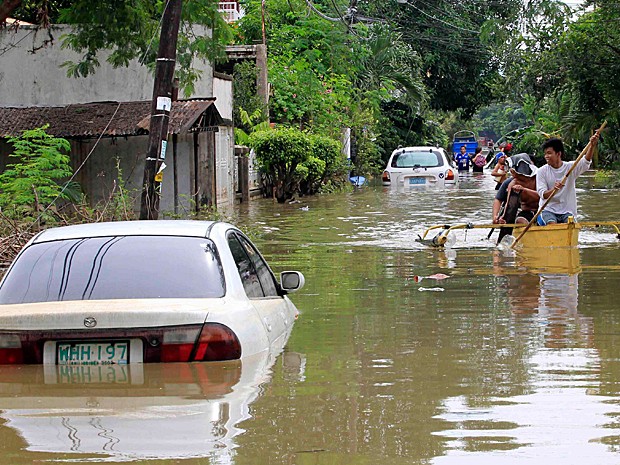 Moradores usam pequeno barco para atravessar rua inundada pela tempestade tropical nas Filipinas (Foto: Romeo Ranoco/Reuters)