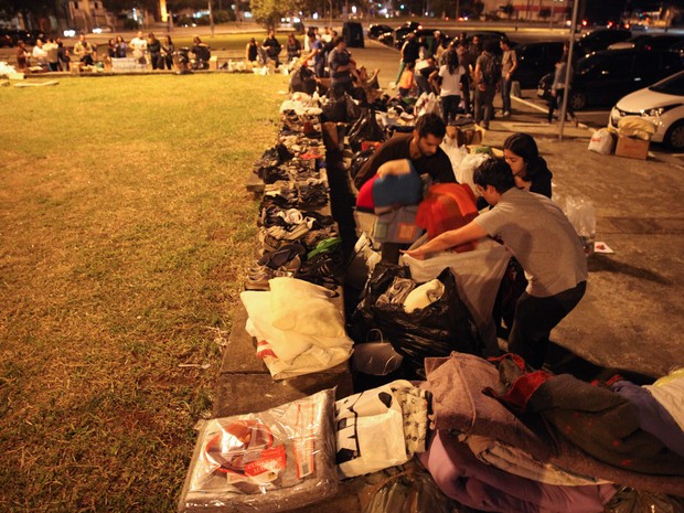 Às 21h da última terça-feira do mês, dezenas de pessoas se reúnem na Praça Charles Miller, no Pacaembu, e organizam uma 'linha de produção' para separar doações de cobertores, roupas, alimentos e material de higiene bucal antes de sair por São Paulo (Foto: Fábio Tito/G1)