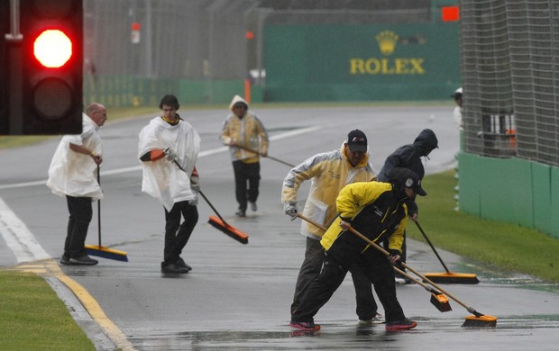 Fiscais tentam tirar a água da pista de Melbourne, no treino classificatório para o GP da Austrália  (Foto: AP)
