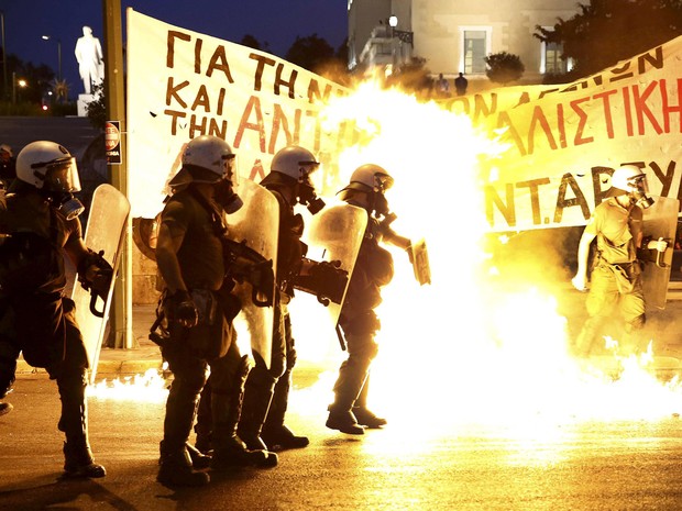 Policiais passam por chamas durante confronto com um pequeno grupo de manifestantes anti-austeridade em frente ao parlamento em Atenas, na Grécia (Foto: Yannis Behrakis/Reuters)