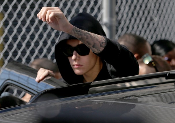 Justin Bieber acena para os fãs ao sair da prisão (Foto: Getty Images)