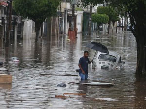 Homem tenta atravessar região alagada pela chuva na Avenida Zaki Narchi, altura da Rua Urupiara, na Zona Norte de São Paulo, no final da tarde desta sexta-feira (24). (Foto: Alex Silva/Estadão Conteúdo)