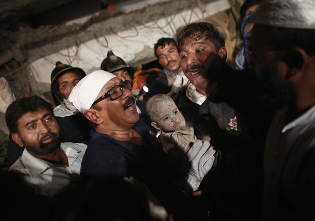 Criança resgatada com vida dos escombros (Foto: Vivek Prakash/Reuters)